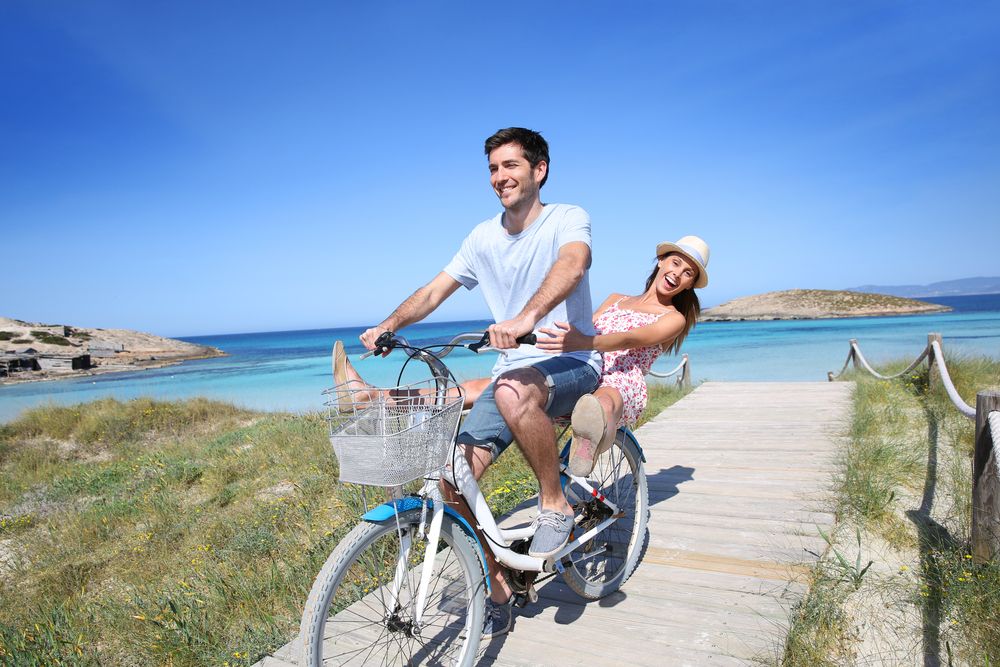 Man and Woman riding a bike on the beach